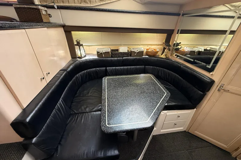 Slide: The Image of 1999 Carver 406 Aft Cabin Motor Yacht interior with black leather seating and dining table. - 18