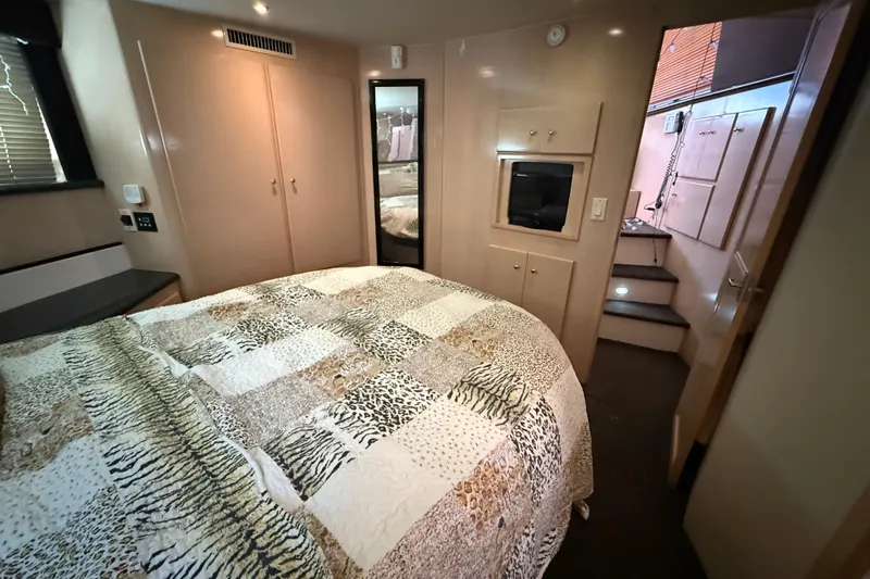 Slide: The Image of 1999 Carver 406 Aft Cabin Motor Yacht bedroom with patterned bedding and modern amenities. - 24