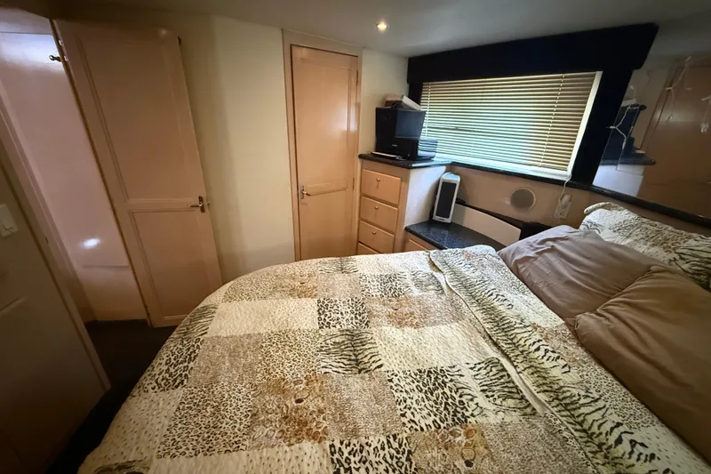Slide: The Image of 1999 Carver 406 Aft Cabin Motor Yacht bedroom with patterned bedding and wooden cabinetry. - 25