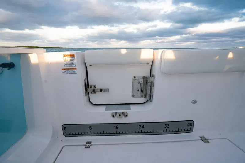 Slide: The Image of 2025 Sea Fox 268 Commander boat interior with measurement scale and latch, under cloudy sky. - 25