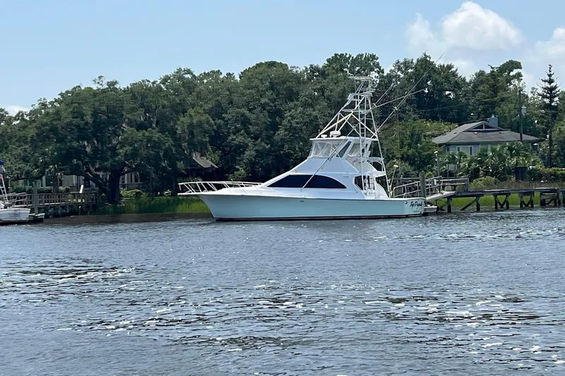 Slide: The Image of 1996 Ocean Yachts 48 Super Sport docked by lush greenery. - 2