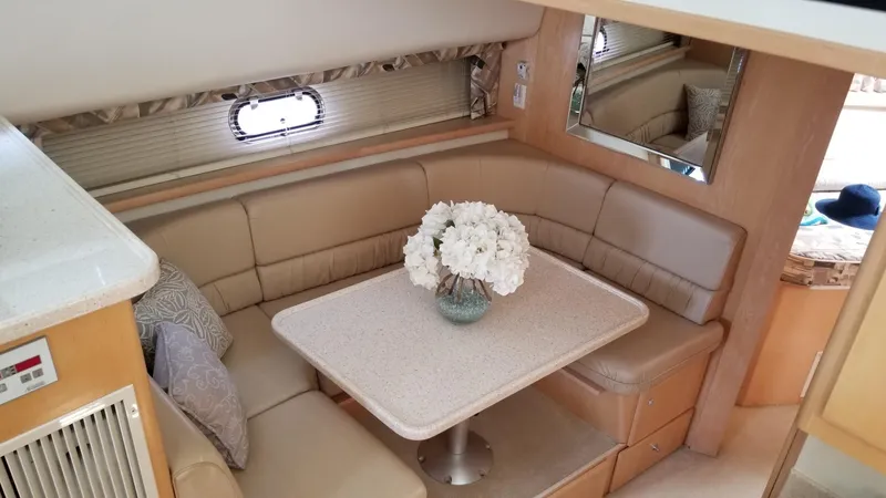 Slide: The Image of 1998 Carver 445 Aft Cabin Motor Yacht interior with cozy dining area and floral centerpiece. - 27
