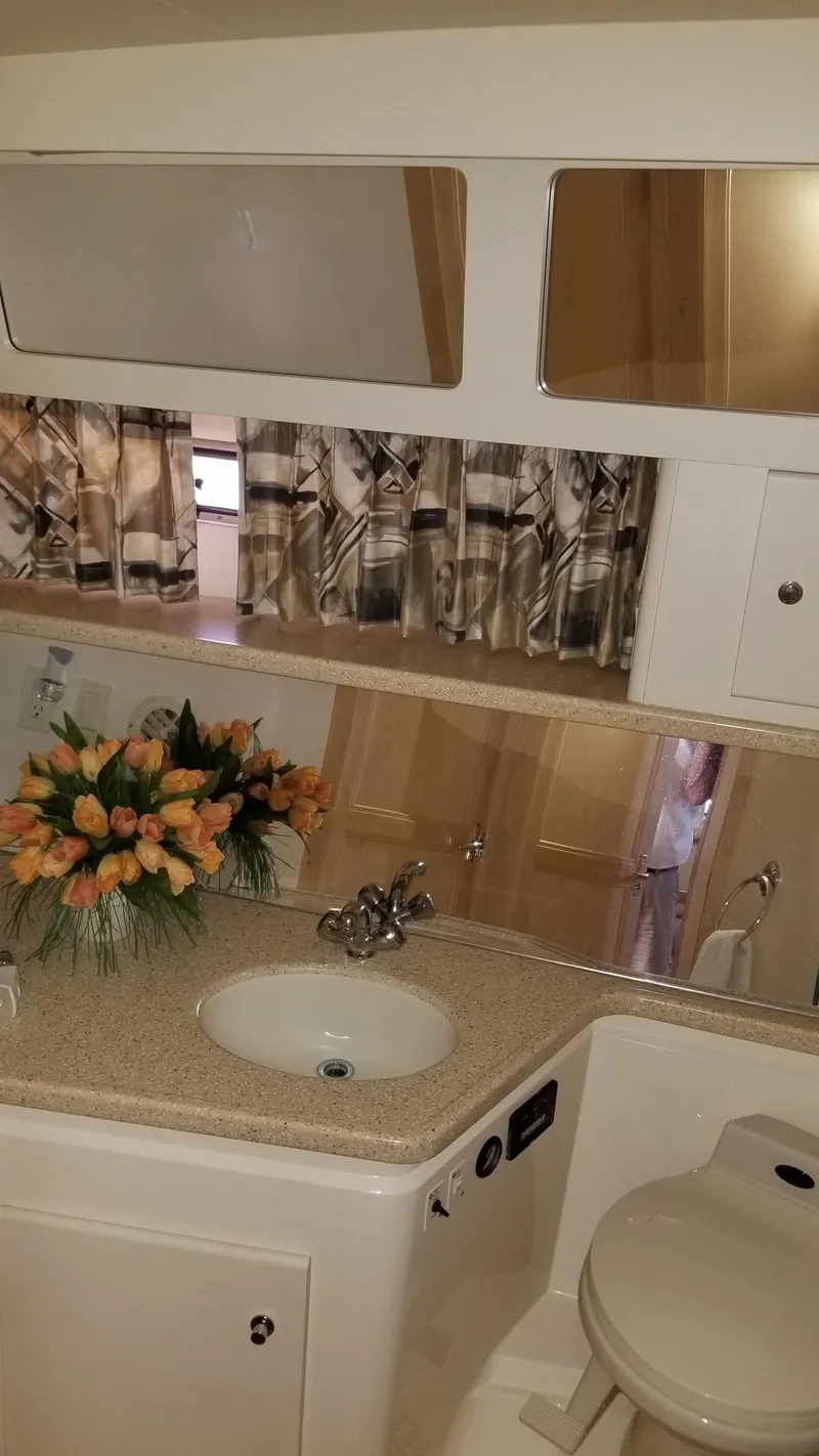 Slide: The Image of 1998 Carver 445 Aft Cabin Motor Yacht bathroom with sink, mirror, and floral arrangement. - 37