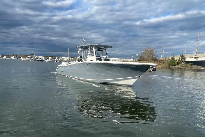 Slide: The Image of 2025 Tidewater 302 CC Adventure boat on calm water under cloudy sky. - 10