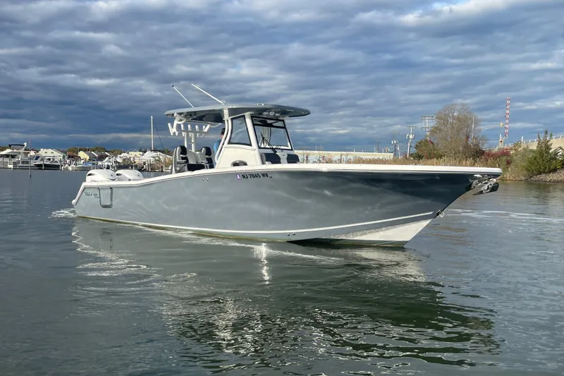 Slide: The Image of 2025 Tidewater 302 CC Adventure boat cruising on calm waters under cloudy skies. - 11
