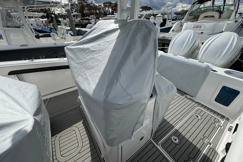Slide: The Image of 2025 Tidewater 302 CC Adventure boat interior with protective covers, docked at marina. - 116