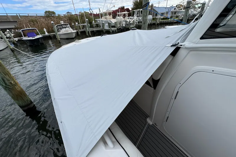 Slide: The Image of 2025 Tidewater 302 CC Adventure boat with protective cover docked at marina. - 117