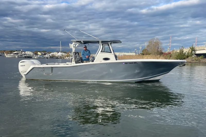 Slide: The Image of 2025 Tidewater 302 CC Adventure boat cruising on a calm waterway under cloudy skies. - 12