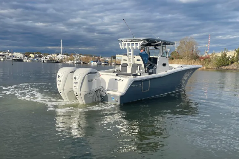 Slide: The Image of 2025 Tidewater 302 CC Adventure boat with dual Yamaha engines on a calm waterway. - 13