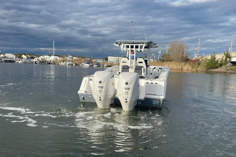 Slide: The Image of 2025 Tidewater 302 CC Adventure boat with dual engines on a calm waterway. - 15