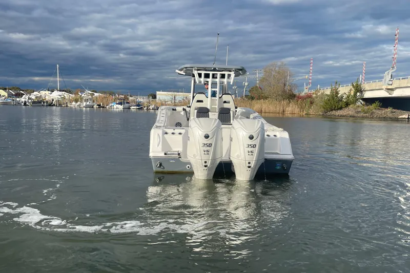 Slide: The Image of 2025 Tidewater 302 CC Adventure boat with dual 350 V6 engines on a calm waterway. - 16