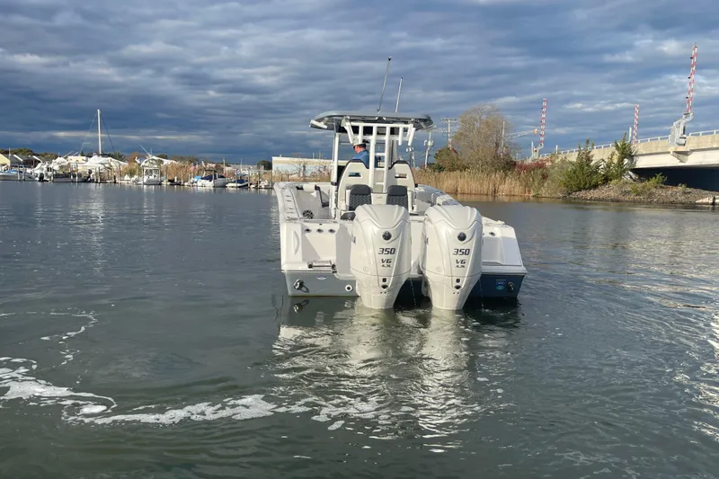 Slide: The Image of 2025 Tidewater 302 CC Adventure boat with dual engines on a calm waterway. - 17