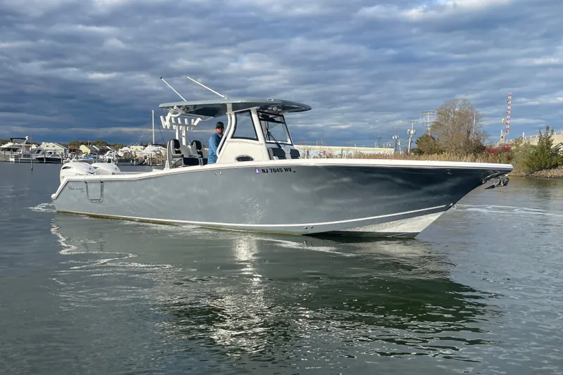 The Image of 2025 Tidewater 302 CC Adventure boat cruising on a calm waterway under cloudy skies. - 2