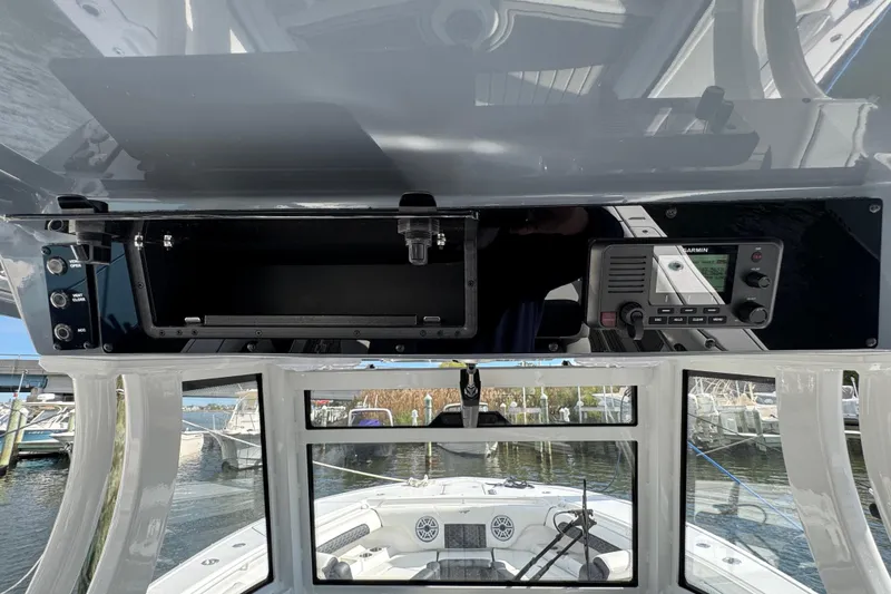 Slide: The Image of 2025 Tidewater 302 CC Adventure boat dashboard with navigation equipment and open storage compartment. - 38