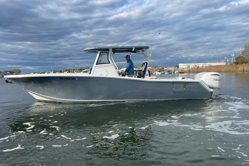 Slide: The Image of 2025 Tidewater 302 CC Adventure boat cruising on a calm waterway under cloudy skies. - 5