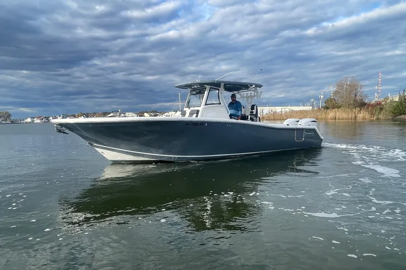 Slide: The Image of 2025 Tidewater 302 CC Adventure boat cruising on calm waters under cloudy skies. - 6