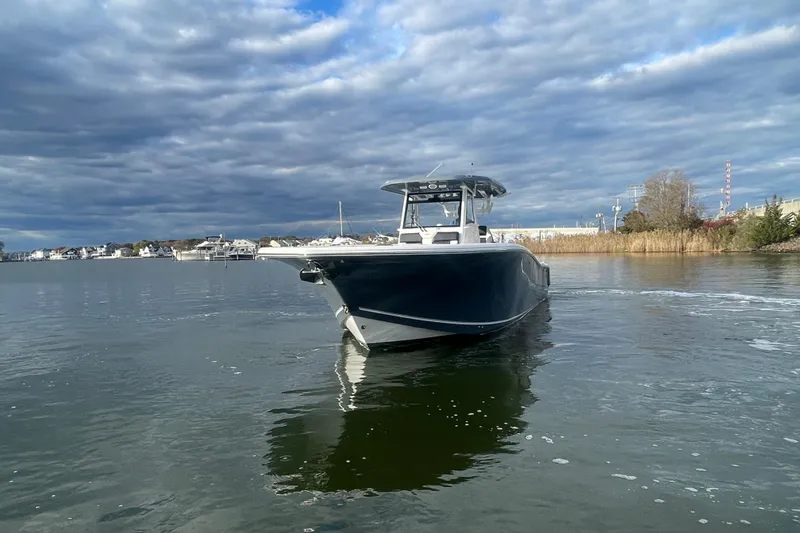 Slide: The Image of 2025 Tidewater 302 CC Adventure boat on calm water under cloudy sky. - 8