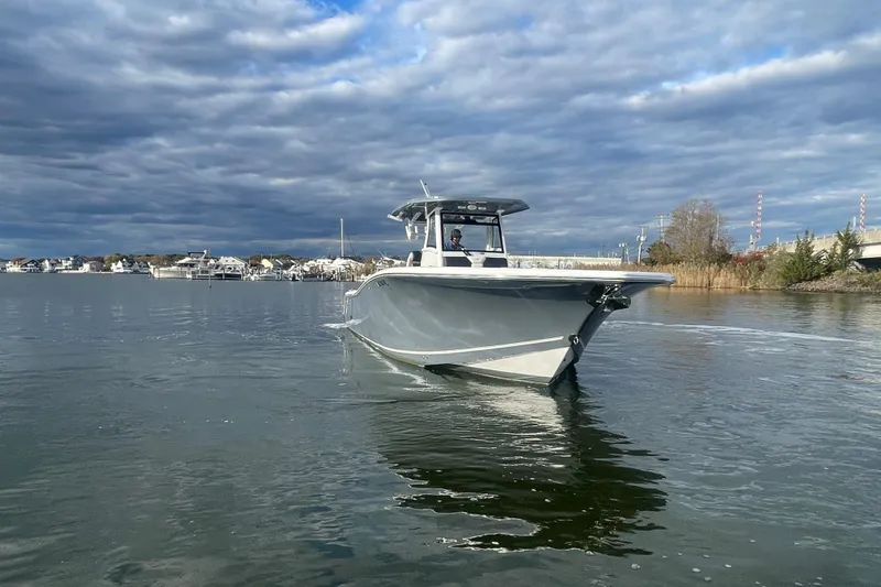 Slide: The Image of 2025 Tidewater 302 CC Adventure boat cruising on a calm waterway under cloudy skies. - 9