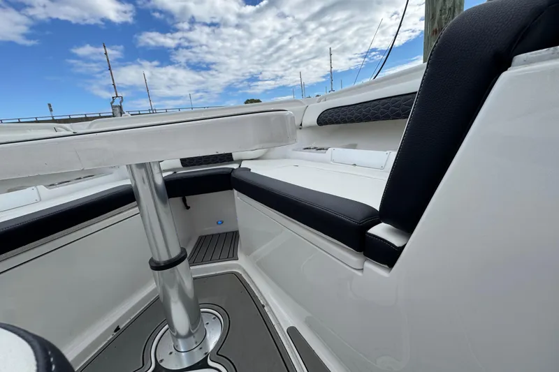 Slide: The Image of 2025 Tidewater 302 CC Adventure boat interior with sleek seating and table under a blue sky. - 93