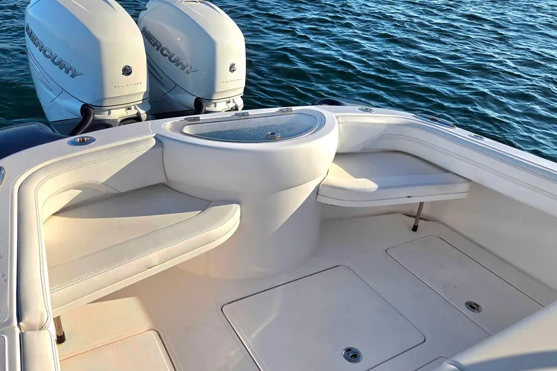 Slide: The Image of 2022 Mag Bay 33 CC boat interior with twin Mercury engines, featuring white seating and storage. - 10