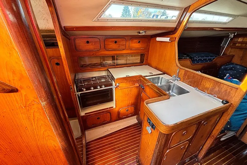 Slide: The Image of Interior of 1986 Beneteau First 42 sailboat, featuring a wooden kitchen with stove and sink. - 10