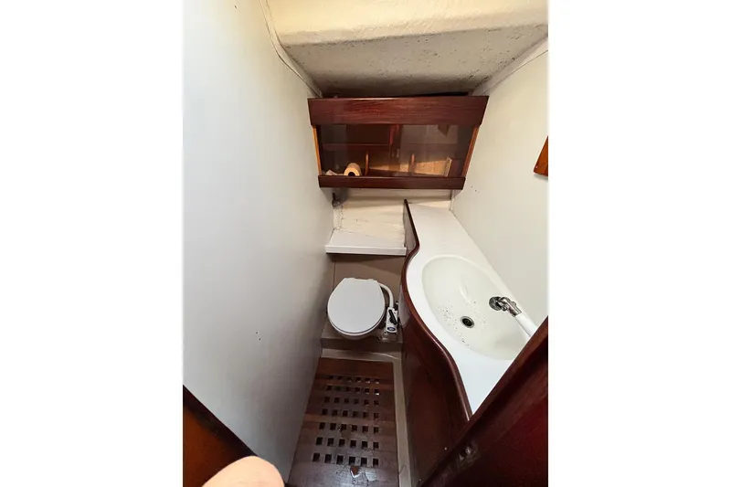 Slide: The Image of 1986 Beneteau First 42 yacht bathroom with sink, toilet, and wooden cabinetry. - 14