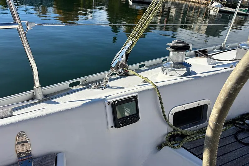 Slide: The Image of 1986 Beneteau First 42 sailboat deck with winch and ropes, docked by calm water. - 5