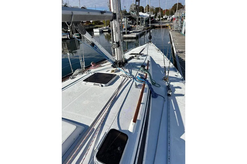 Slide: The Image of 1986 Beneteau First 42 sailboat deck view at marina, showcasing rigging and hatches. - 6