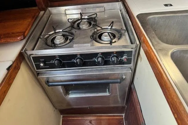 Slide: The Image of 1982 Catalina 38 yacht kitchen with a three-burner stove and oven. - 24