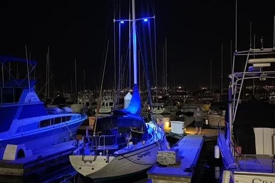 Slide: The Image of 1982 Catalina 38 sailboat docked at night, illuminated by blue lights. - 36