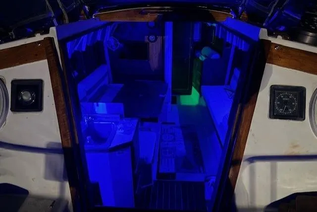 Slide: The Image of 1982 Catalina 38 yacht interior illuminated with blue lighting, showcasing kitchen and seating area. - 39
