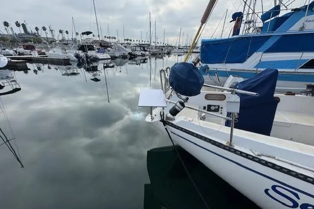 Slide: The Image of 1982 Catalina 38 sailboat docked in a calm marina, reflecting cloudy sky. - 5