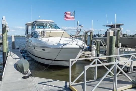 Slide: The Image of 2005 Cruiser Yachts 405 EXPRESS docked with American flag, clear sky background. - 115