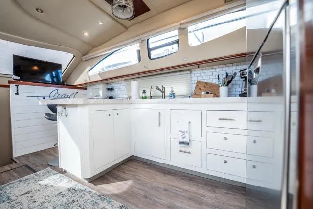 Slide: The Image of Luxurious 2005 Cruiser Yachts 405 EXPRESS interior kitchen with modern white cabinetry and wood flooring. - 24