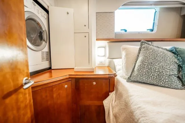 Slide: The Image of 2005 Cruiser Yachts 405 EXPRESS cabin with bed, washer, and wooden cabinetry. - 55