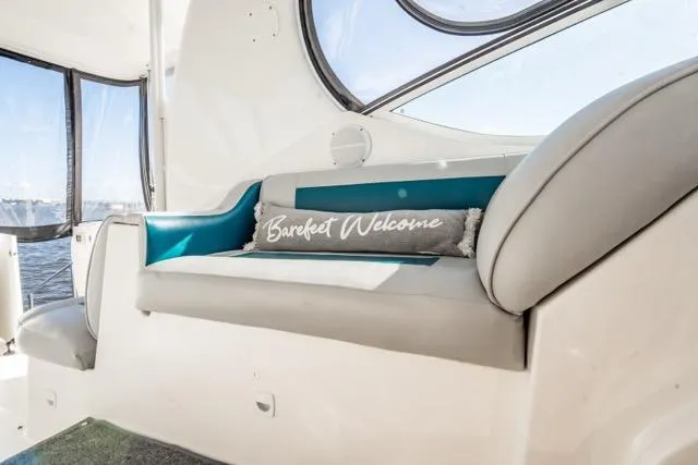 Slide: The Image of 2005 Cruiser Yachts 405 EXPRESS interior with cushioned seating and "Barefeet Welcome" pillow. - 76