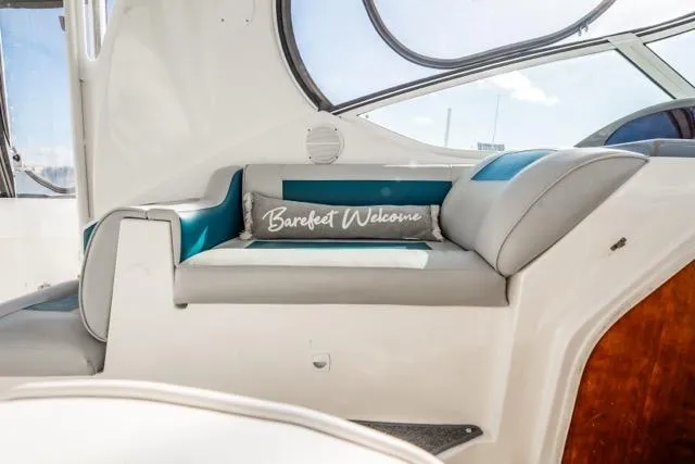 Slide: The Image of 2005 Cruiser Yachts 405 EXPRESS interior with cushioned seating and "Barefoot Welcome" pillow. - 82