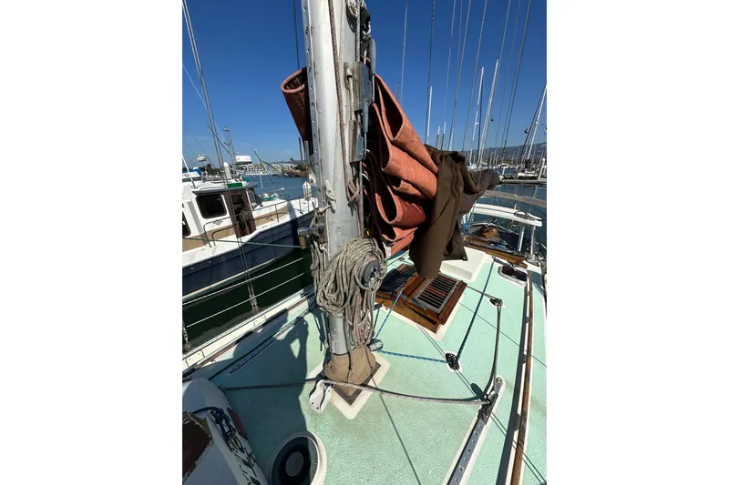 Slide: The Image of 1978 Tayana 37 sailboat deck with mast, ropes, and sails in a marina. - 10