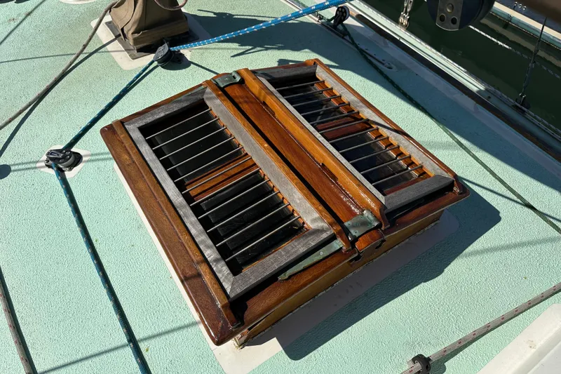 Slide: The Image of Wooden hatch on 1978 Tayana 37 sailboat deck, featuring metal bars and ropes. - 11