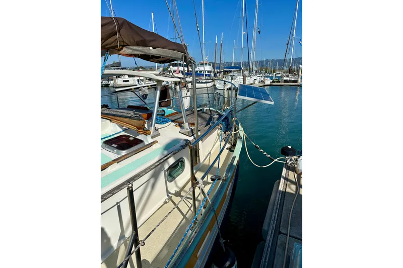 Slide: The Image of 1978 Tayana 37 sailboat docked, featuring solar panel and marina background. - 13