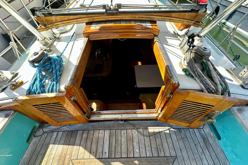Slide: The Image of 1978 Tayana 37 sailboat cockpit with open wooden hatch and visible ropes. - 19