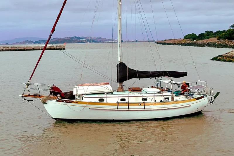Slide: The Image of 1978 Tayana 37 sailboat anchored in a calm bay with scenic background. - 2
