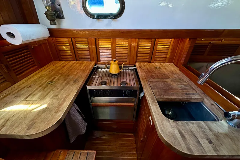 Slide: The Image of 1978 Tayana 37 yacht galley with wooden countertops, stove, and sink. - 21
