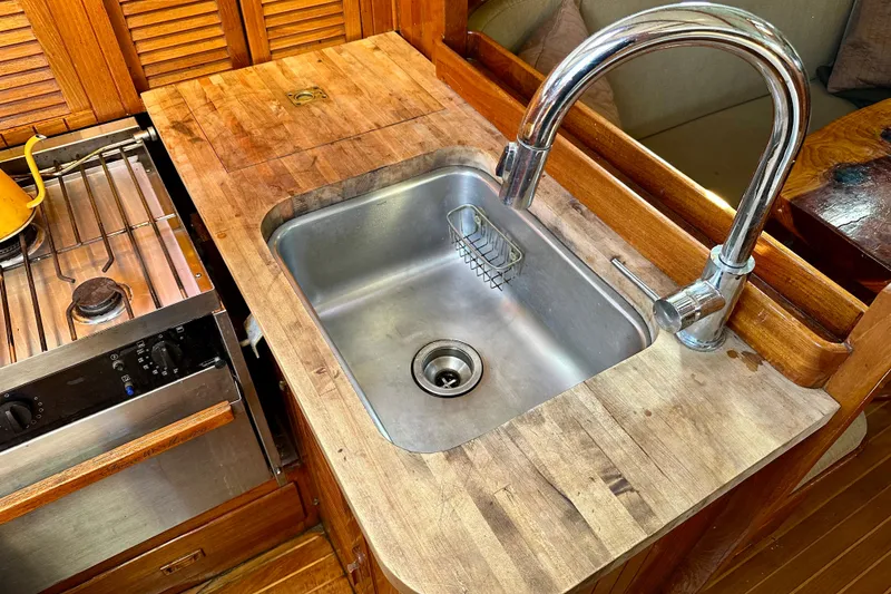 Slide: The Image of Wooden galley kitchen with stainless steel sink and stove on a 1978 Tayana 37 sailboat. - 24