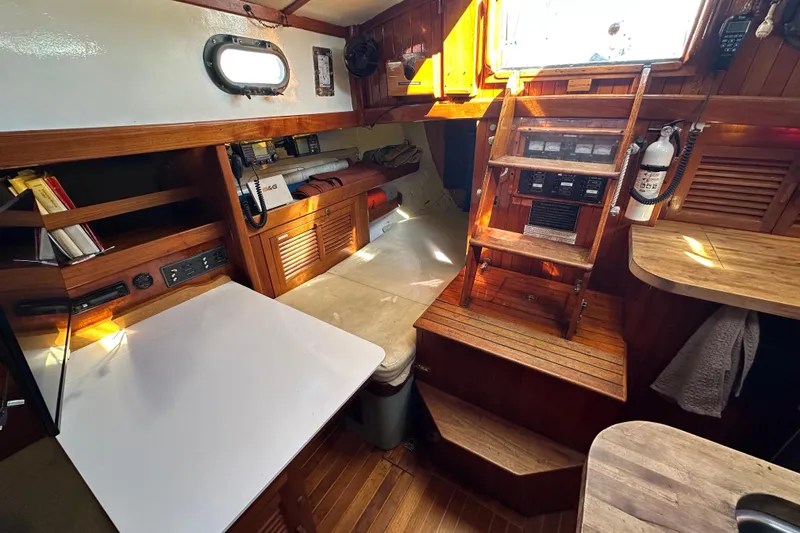 Slide: The Image of 1978 Tayana 37 sailboat interior with wooden cabinetry, navigation table, and ladder. - 26