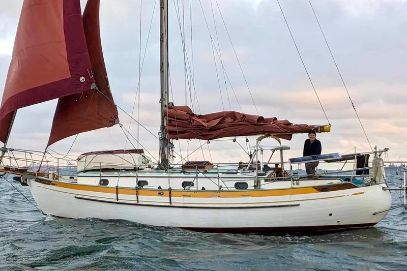 Slide: The Image of 1978 Tayana 37 sailboat with red sails on open water. - 3