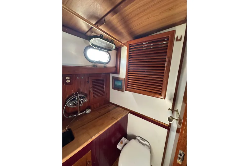 Slide: The Image of 1978 Tayana 37 yacht bathroom with wooden cabinetry and porthole window. - 35