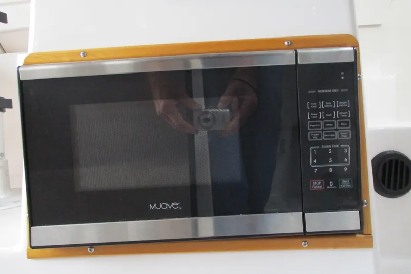 Slide: The Image of Microwave oven inside 2018 Cutwater C-24 boat, featuring digital controls and wood trim. - 27