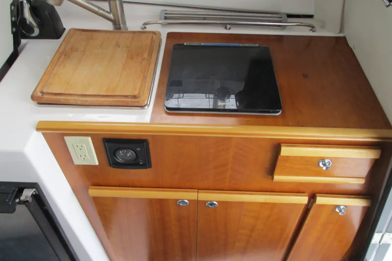 Slide: The Image of 2018 Cutwater C-24 interior with wooden cabinetry and countertop, featuring a cutting board and stove. - 31