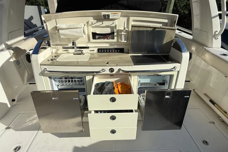 Slide: The Image of 2020 Boston Whaler 420 Outrage boat kitchen with sink, grill, and storage drawers. - 10